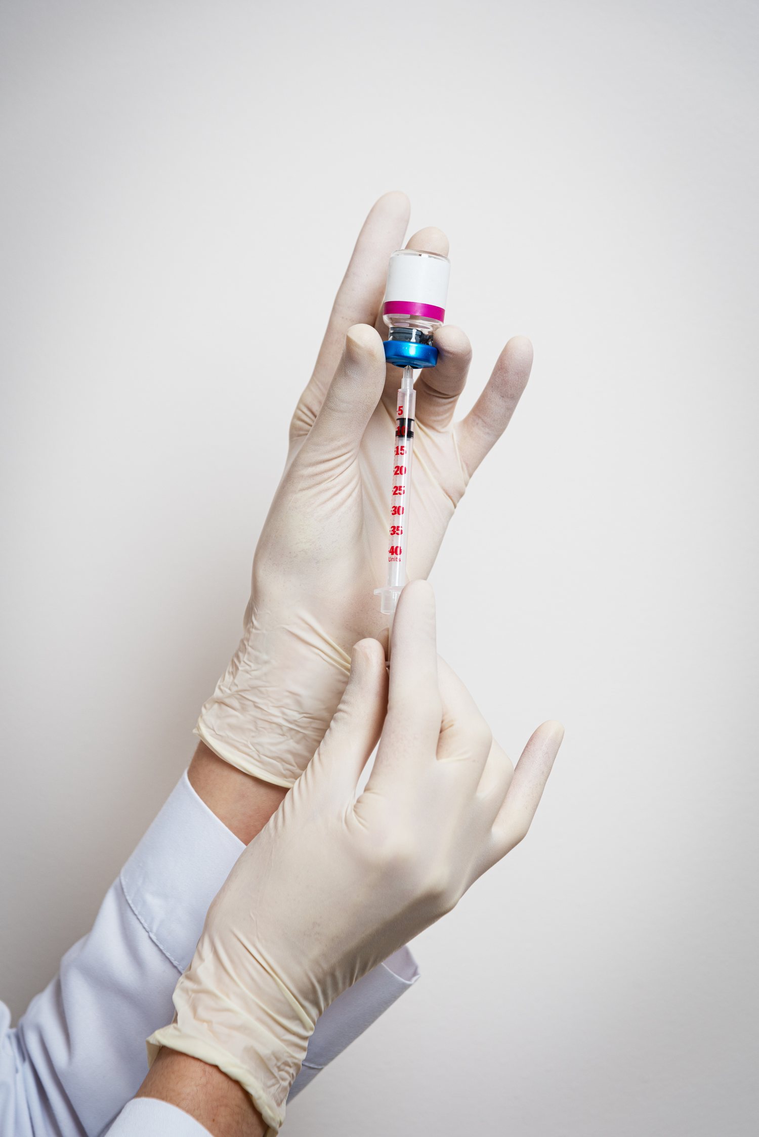 Gloved hands preparing an injection