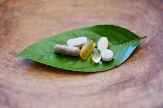 Supplement capsules resting on a green leaf